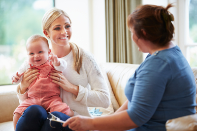 female health visitor talking to mother with young baby